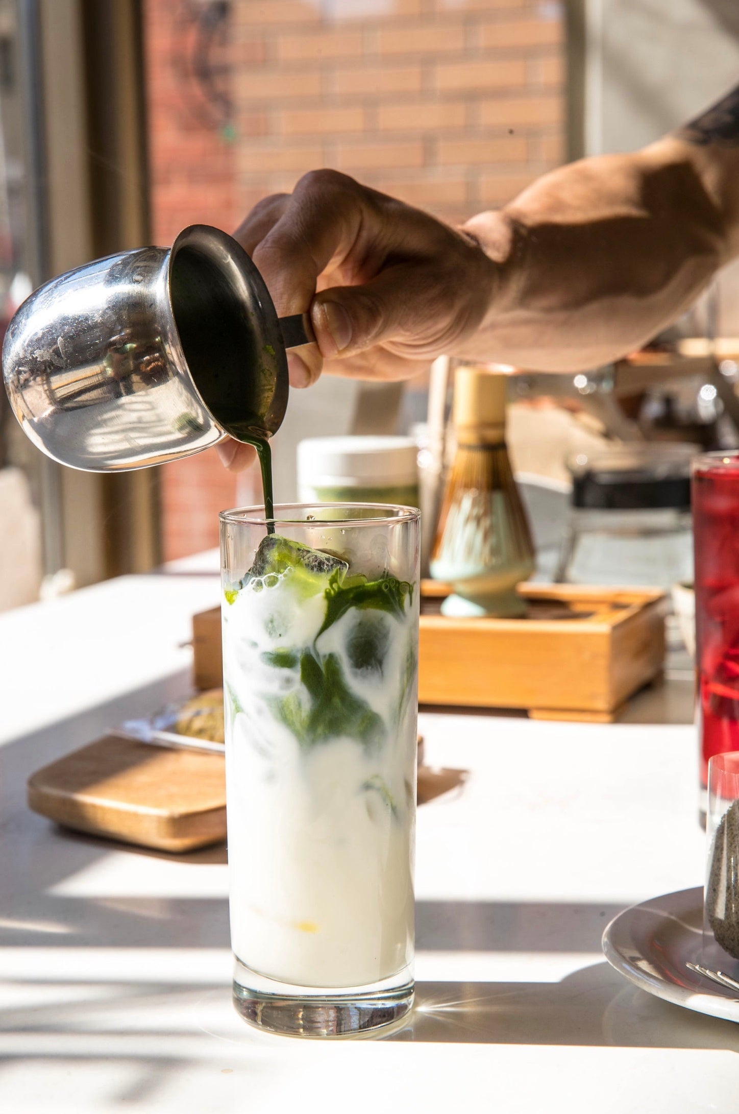 hand-pours-a-green-liquid-into-a-glass-of-ice-and-milk.jpg